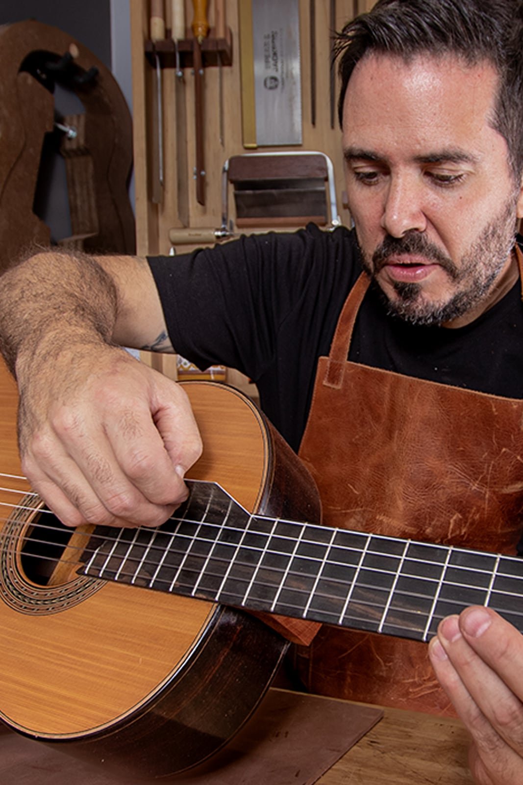 Ricardo revisando de cerca el diapasón de una guitarra terminada